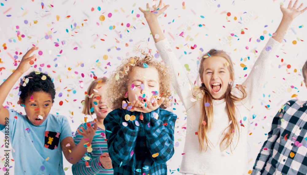 Happy multicultural group of kids having fun during birthday party with confetti